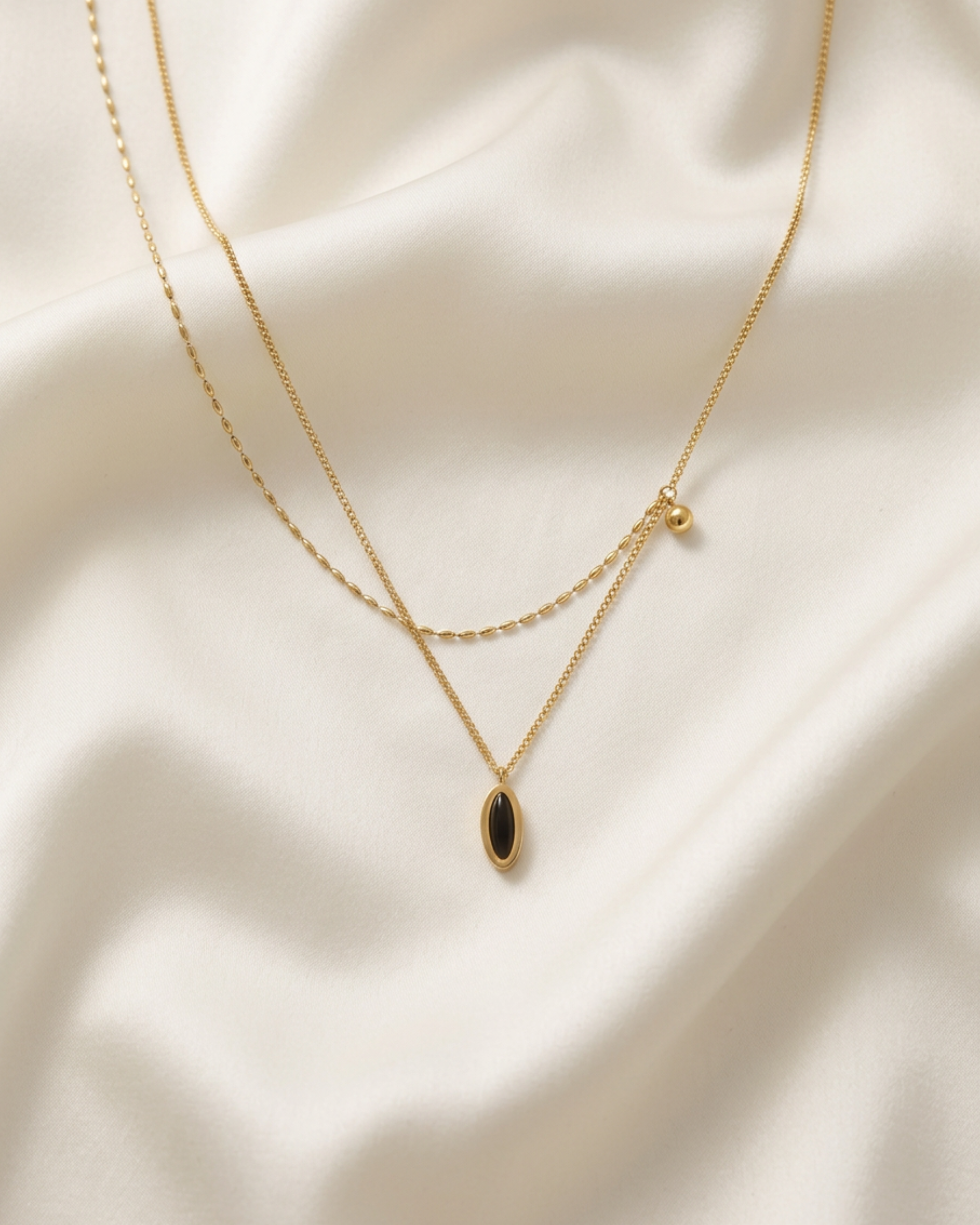 Trove Colombo Cordelia double-layer necklace in 18K gold-plated stainless steel with a black ceramic oval pendant.