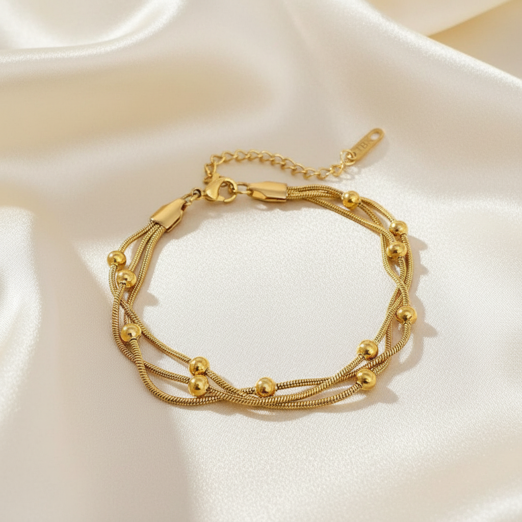 Trove Colombo Seraphina 18K gold plated stainless steel multi-strand bracelet with delicate beads on a white satin background.